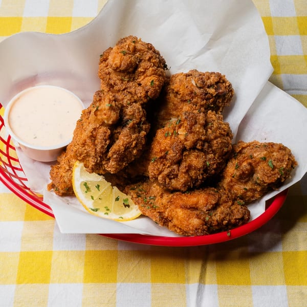 King's Chicken Wings in a red basket with a side of dipping sauce and a lemon wedge.