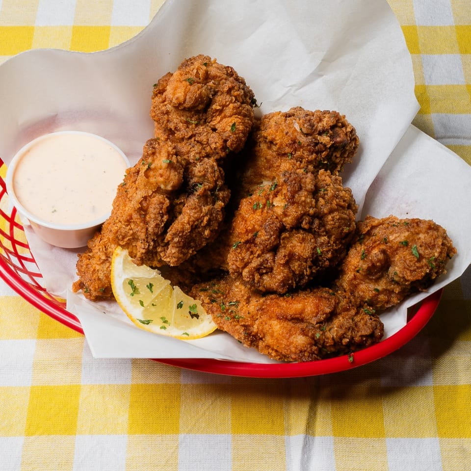 King's Chicken Wings in a red basket with a side of dipping sauce and a lemon wedge.