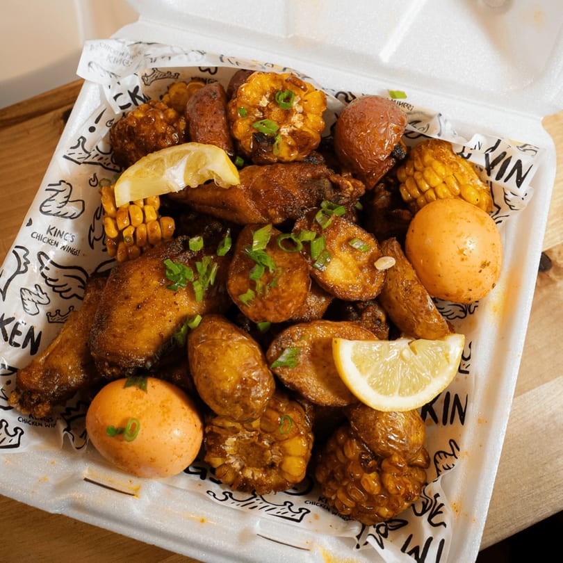 King's Chicken Wings meal with chicken, potatoes, corn, and eggs in a takeout container.