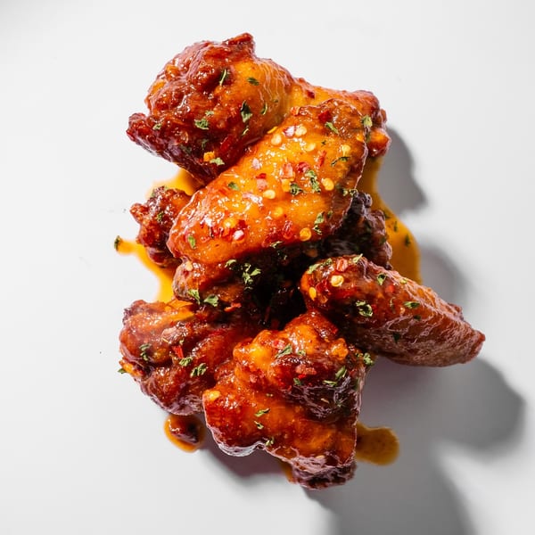 King's Chicken Wings: a pile of glossy, saucy chicken wings with chili flakes and herbs.