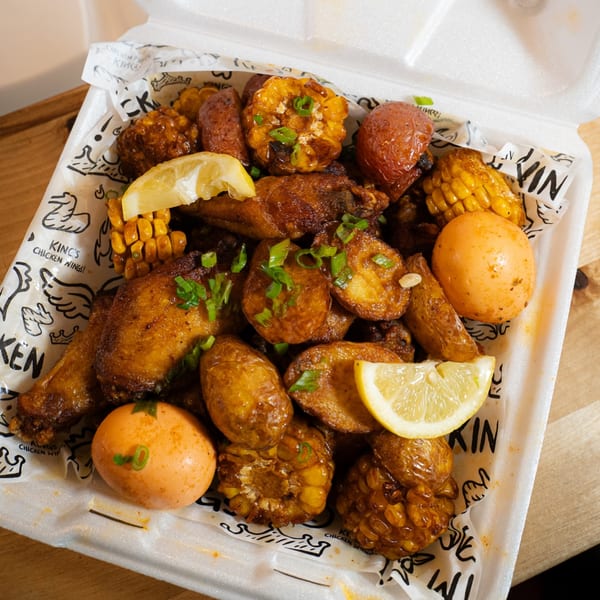 King's Chicken Wings meal with wings, potatoes, corn, and eggs, garnished with lemon and chives.